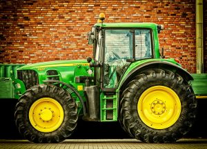 photo of large green farm tractor shown in front of a brick wall