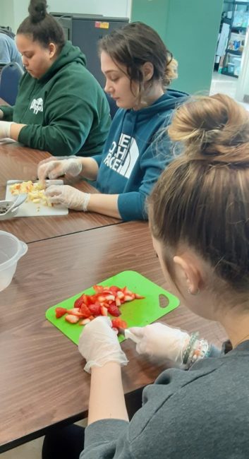 Youth chopping fruit.